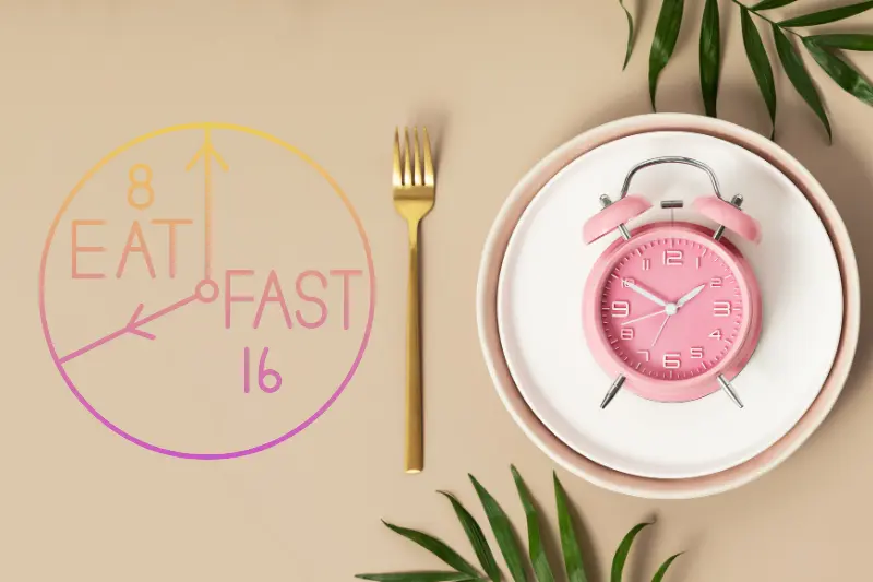 a pink alarm clock on a plate with a fork and a leafy plant